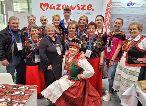 Grupa osób pozuje do zdjęcia na tle napisu 