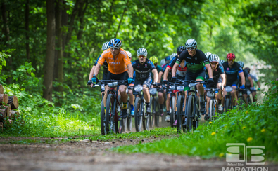 Peleton kolarzy jedzie leśną trasą